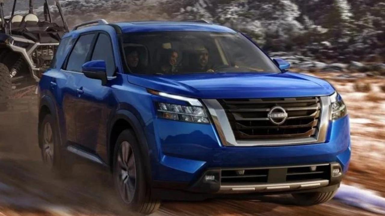 The 8-Seater Nissan Pathfinder in blue while hauling an ATV on a dirt road and a family inside enjoying the ride.